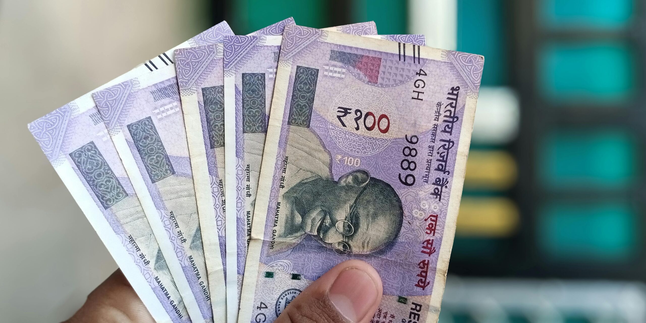 Close-up view of holding Indian 100 rupee banknotes, showcasing currency details and design.
